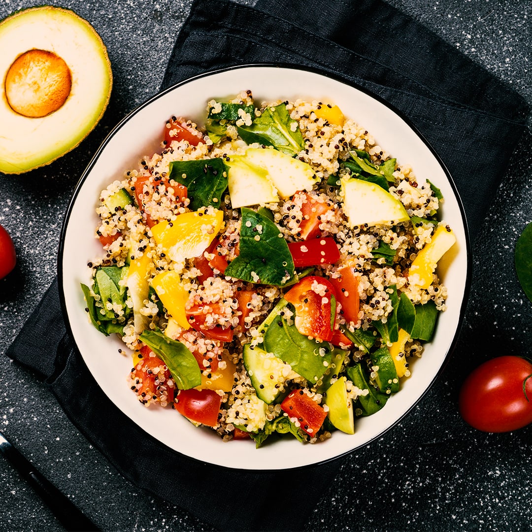 Quinoa salad with fresh vegetables on black.