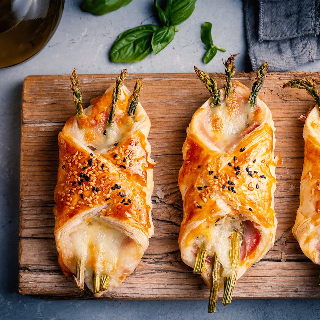 Baked green asparagus with ham and cheese in puff pastry sprinkl